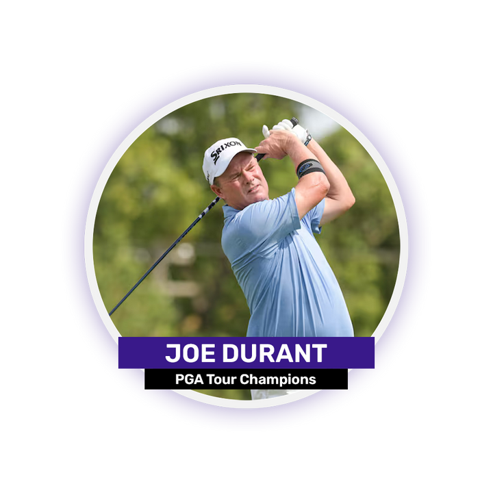A man in a blue shirt and white cap swings a golf club outdoors.