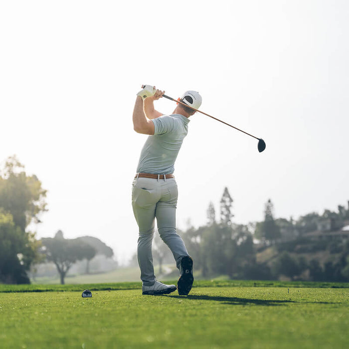 A person on a golf course swings a golf club.
