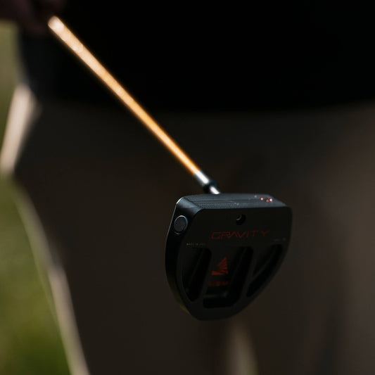 A close-up of a black Gravity golf putter head with a wooden shaft.