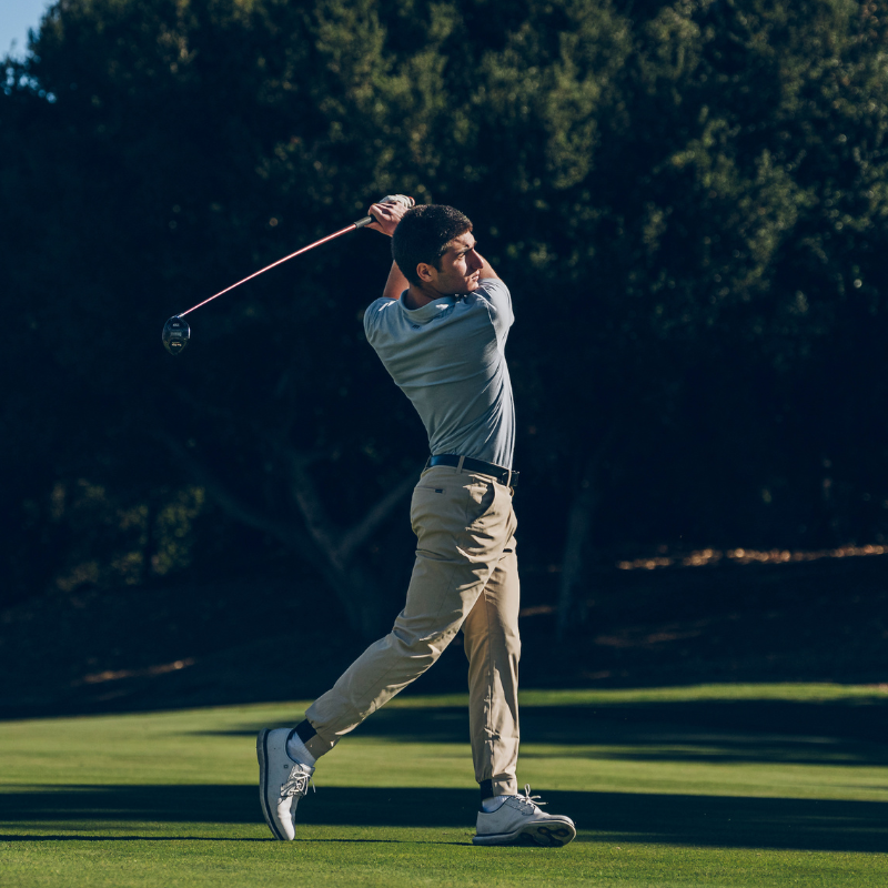 A person swinging a golf club on a lush green golf course.